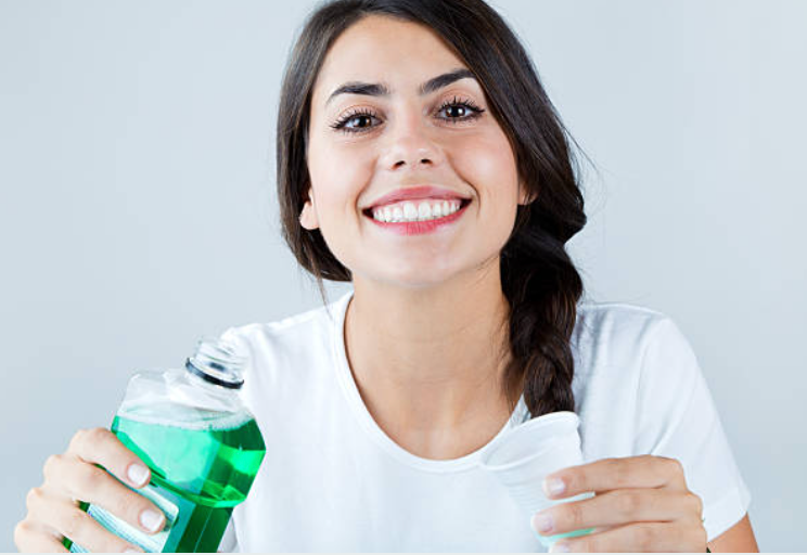 girl smiling and holding mouthwash in her hand