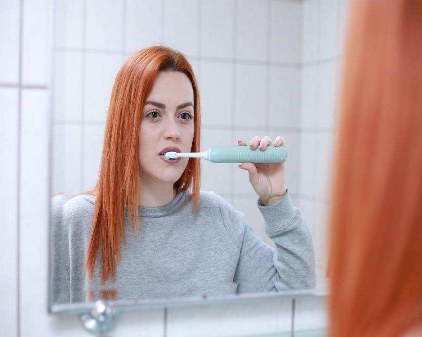 a red-hair woman brushing her teeth